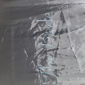 White satin robe with blue BRIDE EMBROIDERED on the back.